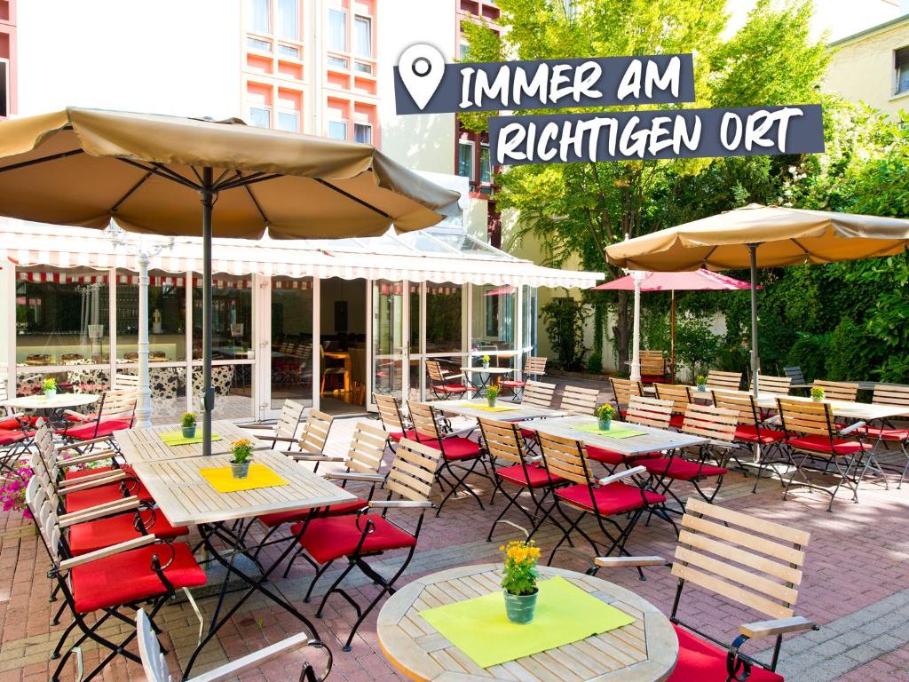 an outdoor patio with tables and chairs and umbrellas at ACHAT Hotel Neustadt an der Weinstraße in Neustadt an der Weinstraße