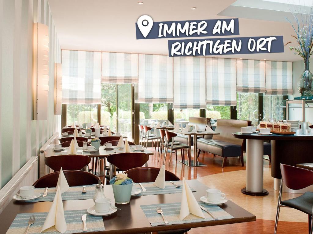 un restaurante con mesas y sillas y un cartel en ACHAT Hotel Regensburg im Park, en Regensburg