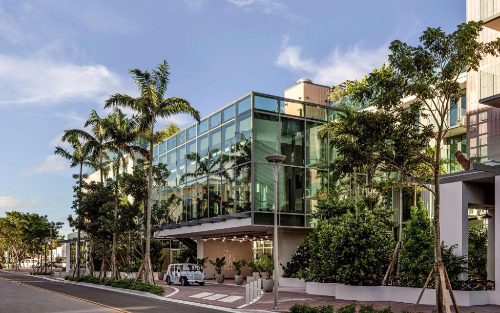 un edificio de cristal con árboles delante de él en The Ray Hotel Delray Beach, Curio Collection By Hilton, en Delray Beach