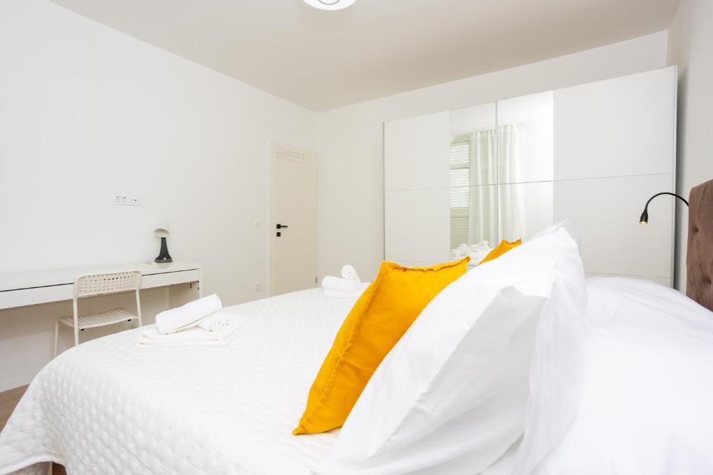 a white bedroom with a large bed with yellow pillows at Miranda's Place in Split