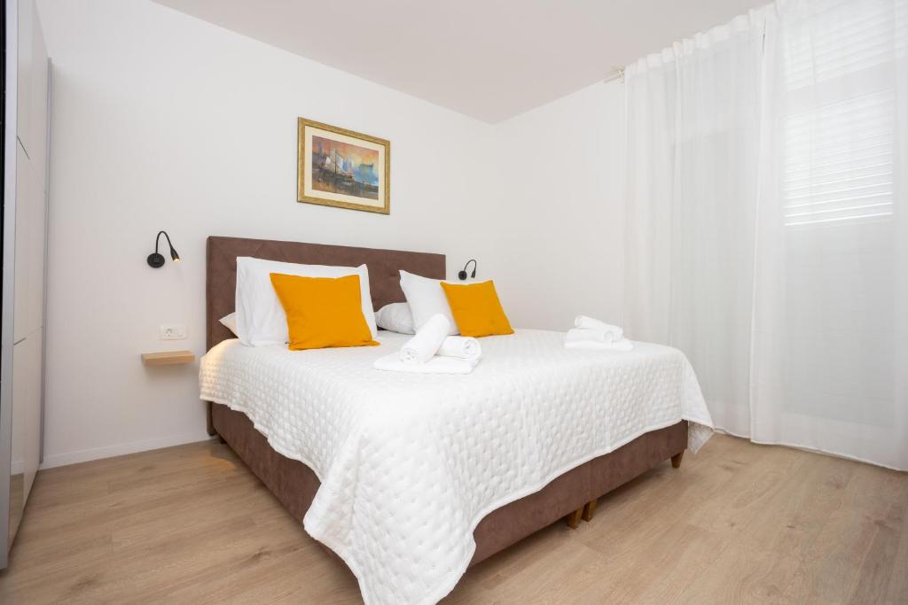 a white bedroom with a large bed with yellow pillows at Miranda's Place in Split