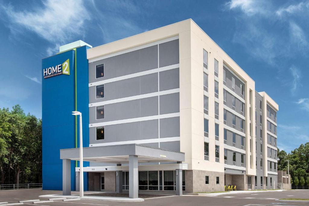 a large white building with a blue sign in front of it at Home2 Suites By Hilton Tampa Westshore Airport, Fl in Tampa