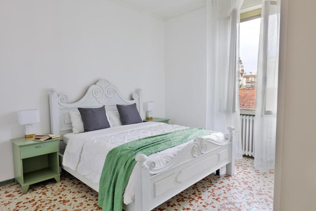a white bedroom with a white bed and a window at Riviera dei friori in Bordighera