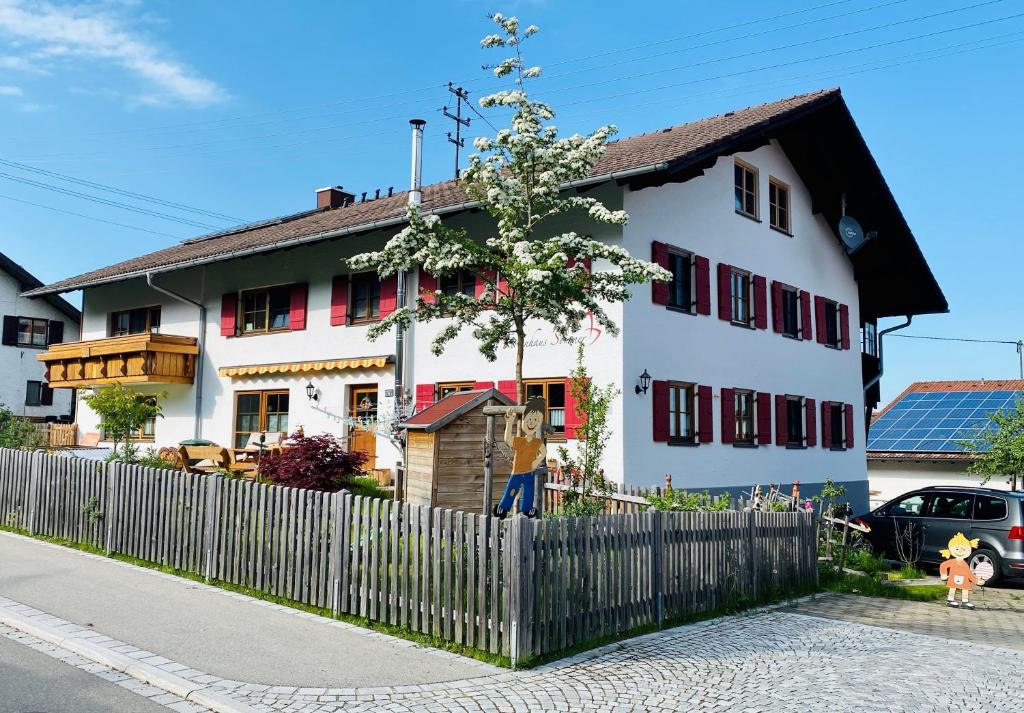 a white house with red windows and a fence at Ferienhaus Sommer in Pfronten