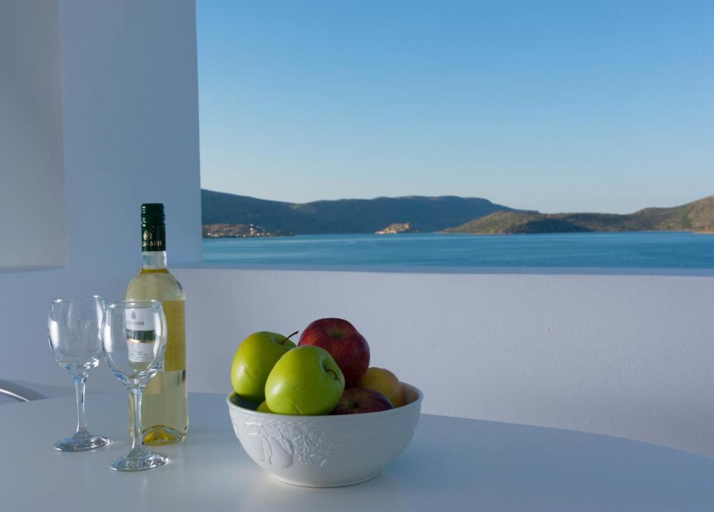 a bowl of fruit and a bottle of wine on a table at Markakis Apartments in Elounda