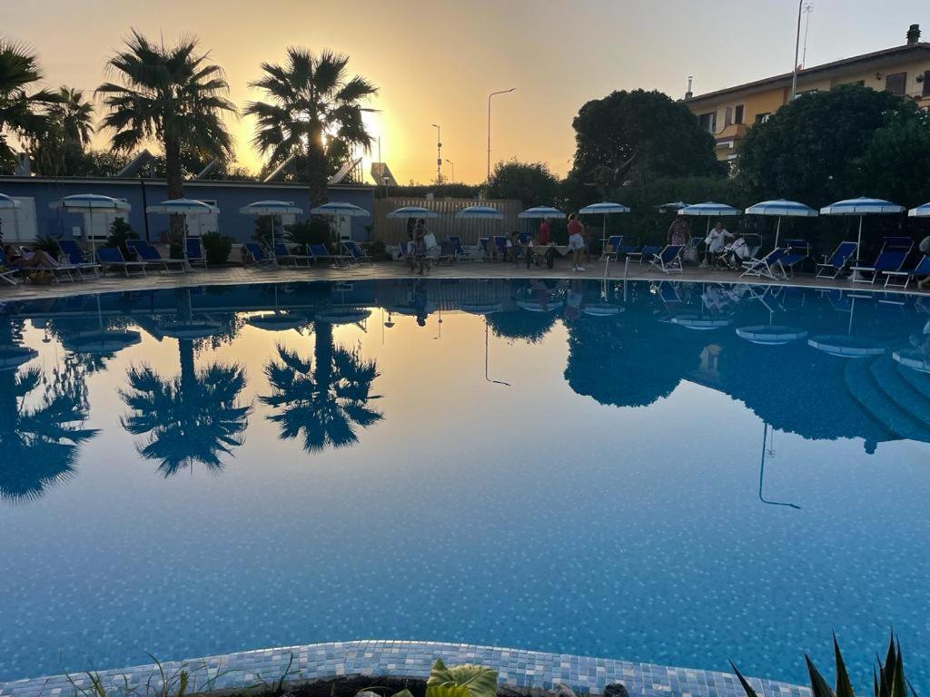 a pool of water with people sitting under umbrellas at Hotel San Gaetano in Grisolia