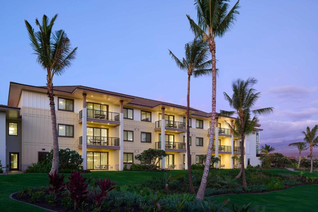 Hilton Grand Vacations Club Maui Bay Villas في كيهي: مبنى كبير أمامه أشجار نخيل