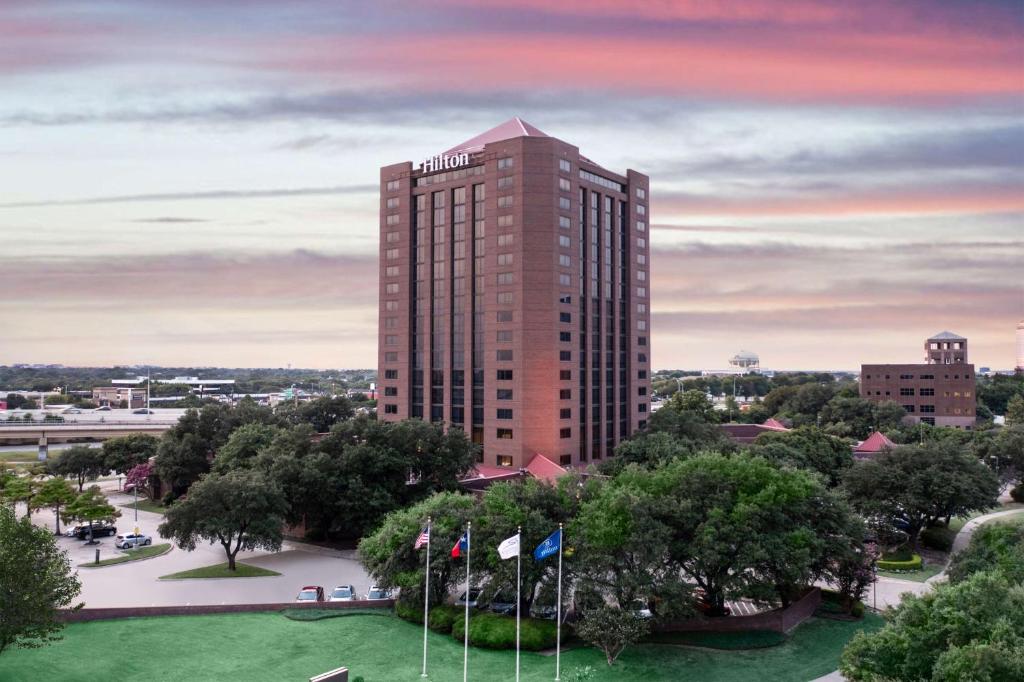 un edificio alto con banderas delante en Hilton Richardson Dallas, TX en Richardson