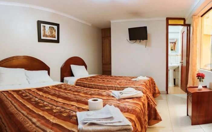 een hotelkamer met 2 bedden en een televisie bij Mallmanya Inn in Cuzco