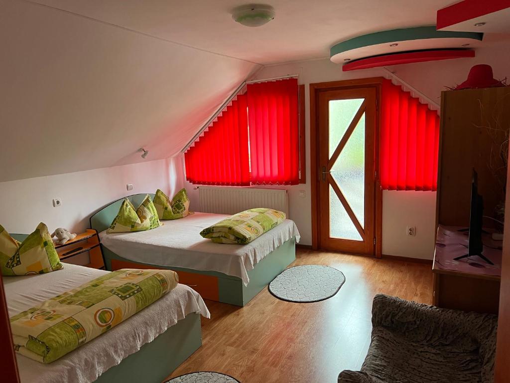 two beds in a room with red curtains at HuniHáz Apartman in Sovata