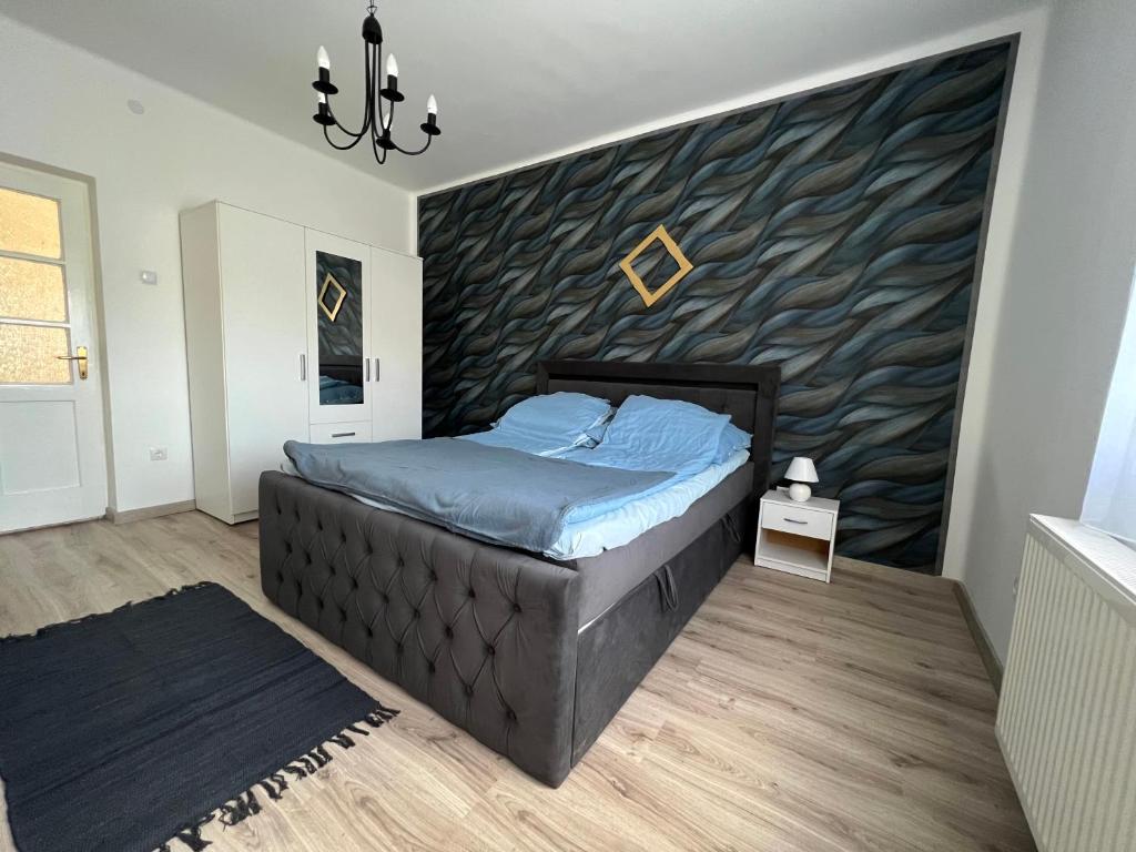 a bedroom with a bed and a wall with waves at AranyLak vendégház in Abádszalók