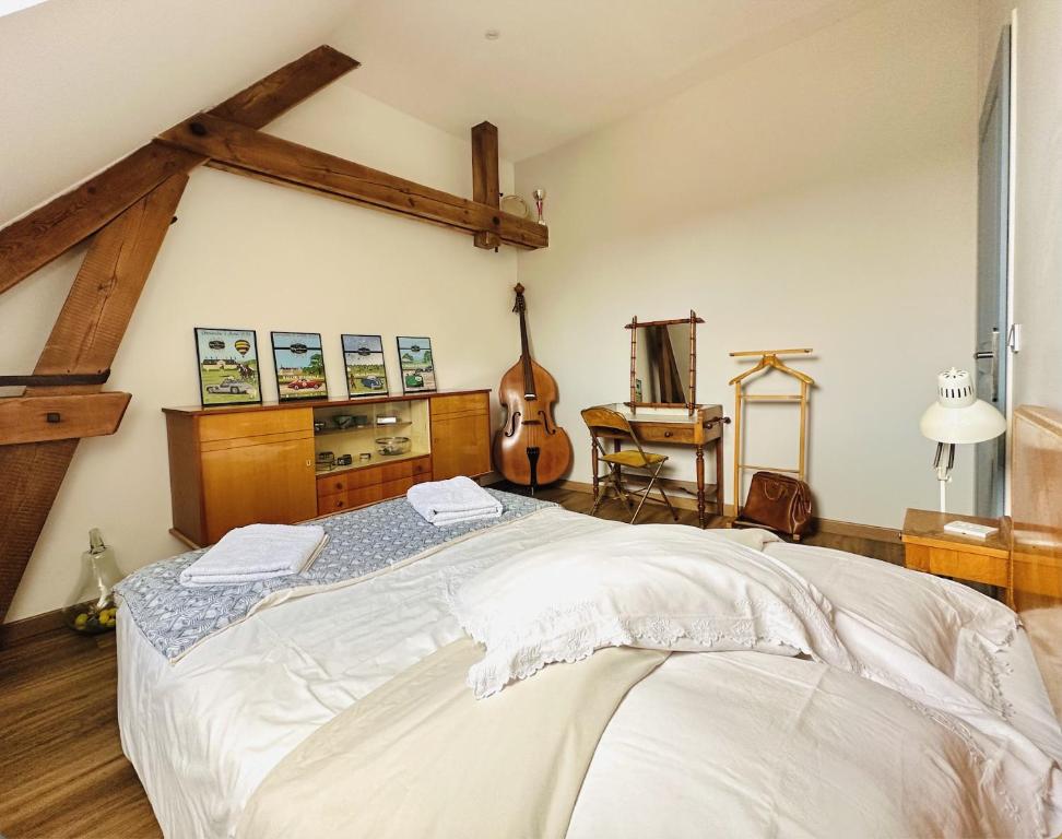 Un dormitorio con una cama grande y una guitarra en La Cour Verte Chambres d'Hôtes, en Montépilloy