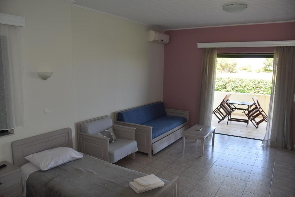 a bedroom with a bed and a couch and a patio at Odysseas rooms in Kalón Nerón