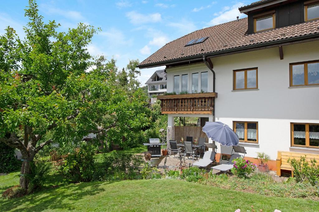 ein Haus mit einem Garten mit Stühlen und einem Sonnenschirm in der Unterkunft Ferienwohnung Blasi mit Alpensicht in Ibach