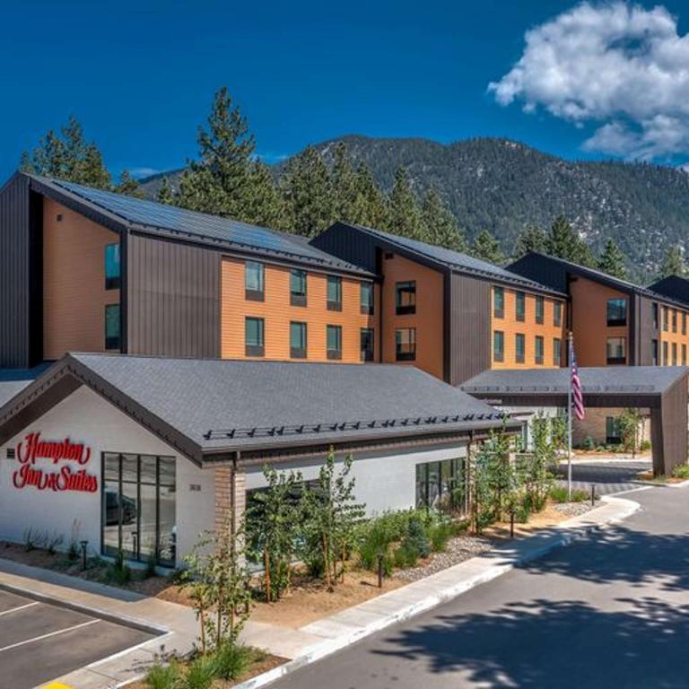 Hampton Inn & Suites South Lake Tahoe في ساوث ليك تاهو: فندق امامه عماره فيها اشجار