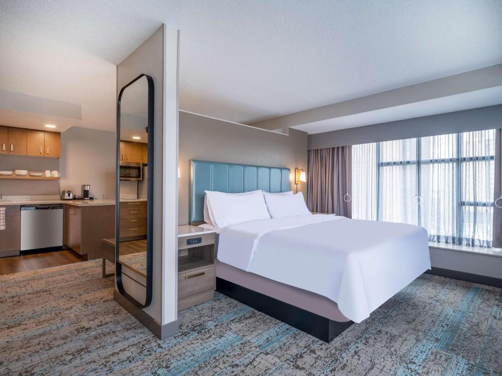 um quarto com uma cama branca e uma grande janela em Homewood Suites By Hilton Toledo Downtown em Toledo