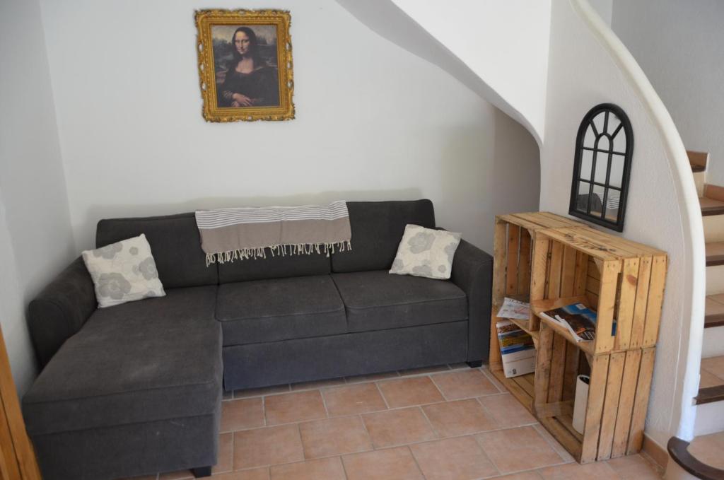 a living room with a black couch and a staircase at Maison Amandre en Pleine Nature - Mas Lou Castanea in Collobrières