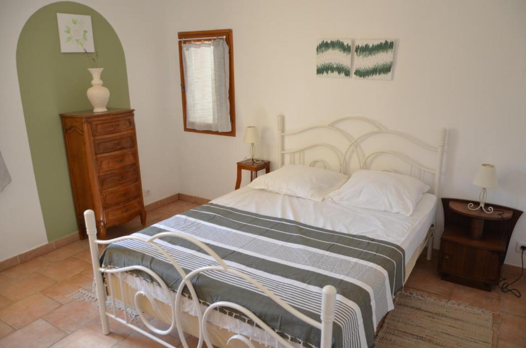 a bedroom with a white bed and a wooden dresser at Maison Amandre en Pleine Nature - Mas Lou Castanea in Collobrières
