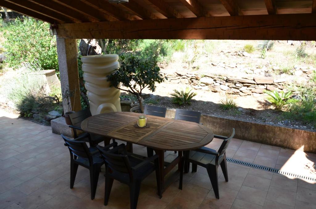 a wooden table and chairs on a patio with a vase at Maison Amandre en Pleine Nature - Mas Lou Castanea in Collobrières