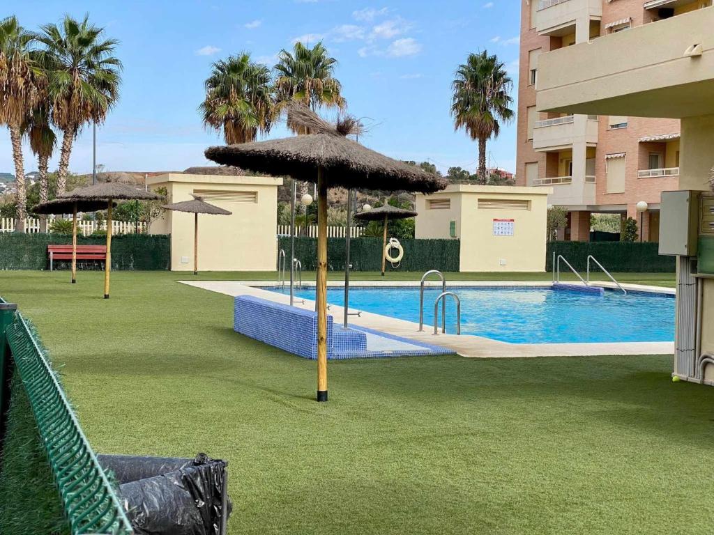 einen Pool mit Sonnenschirmen und einen Pool in der Unterkunft A&N La Vega 10 in Torre del Mar