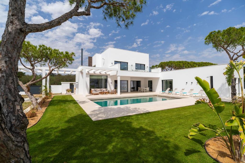 una casa blanca con piscina y patio en ALBA SEA VILLA, en Chiclana de la Frontera