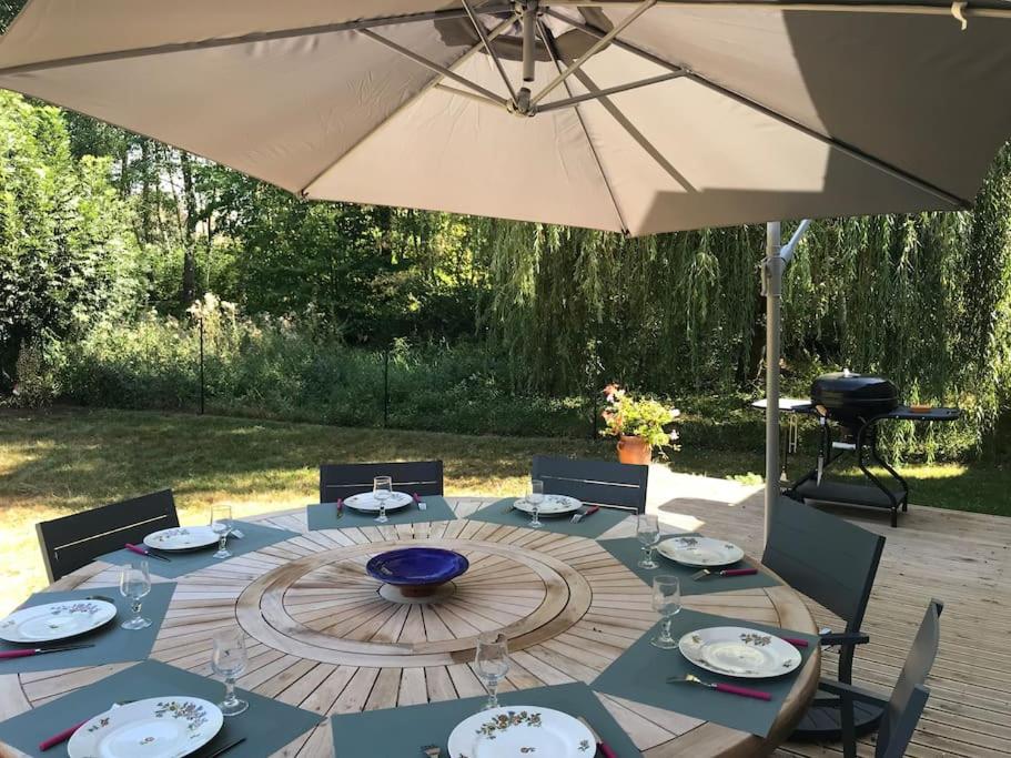 einen Tisch mit einem Sonnenschirm auf einer Terrasse in der Unterkunft Belle dépendance du château : LE LOGIS in Ardentes