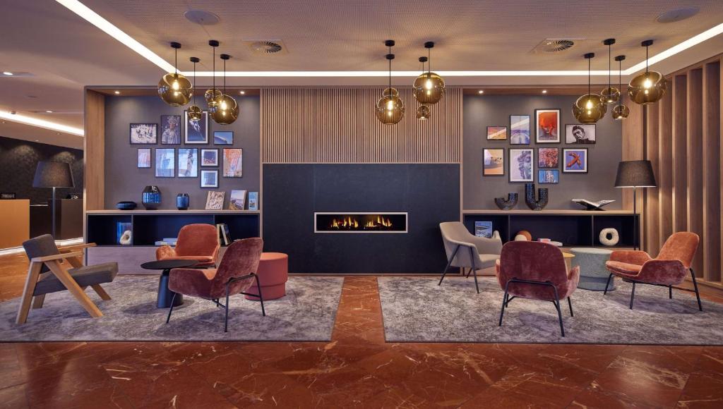 汉诺威DoubleTree by Hilton Hannover Schweizerhof的大厅里有桌椅和壁炉