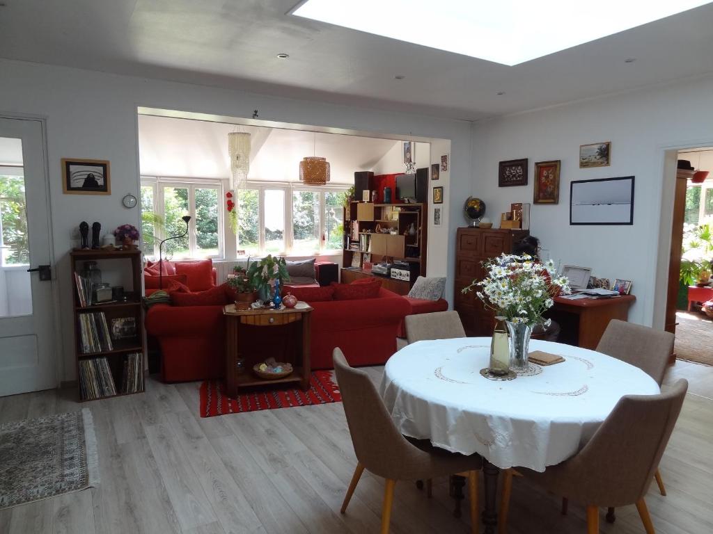 a living room with a table and a red couch at Les Chambres de la Forêt in Juvigny-sous-Andaine