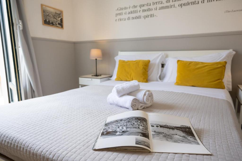 a bedroom with a bed with a book and towels at Casa dei Ré in Siracusa
