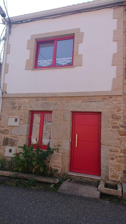 a red door on a brick building with two windows at A Casiña de Carmen in Boiro