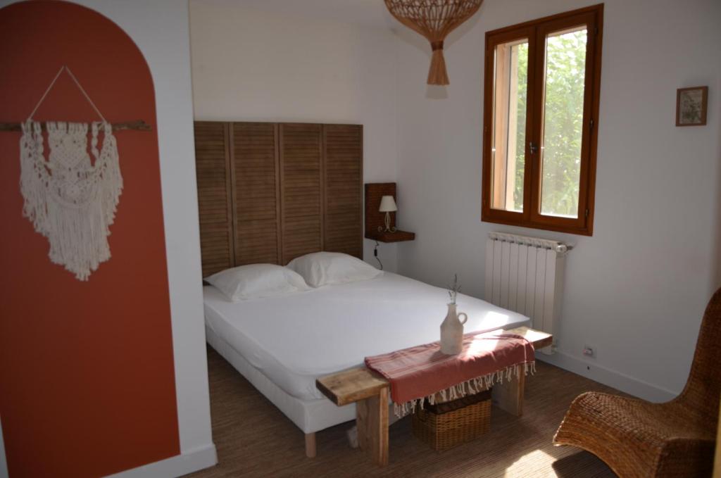 a bedroom with a bed and a table and a window at Maison Amandre en Pleine Nature - Mas Lou Castanea in Collobrières