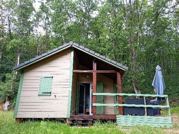 a small house with an umbrella in a field at Chalet les Hameaux du Perrier in Lissac-sur-Couze