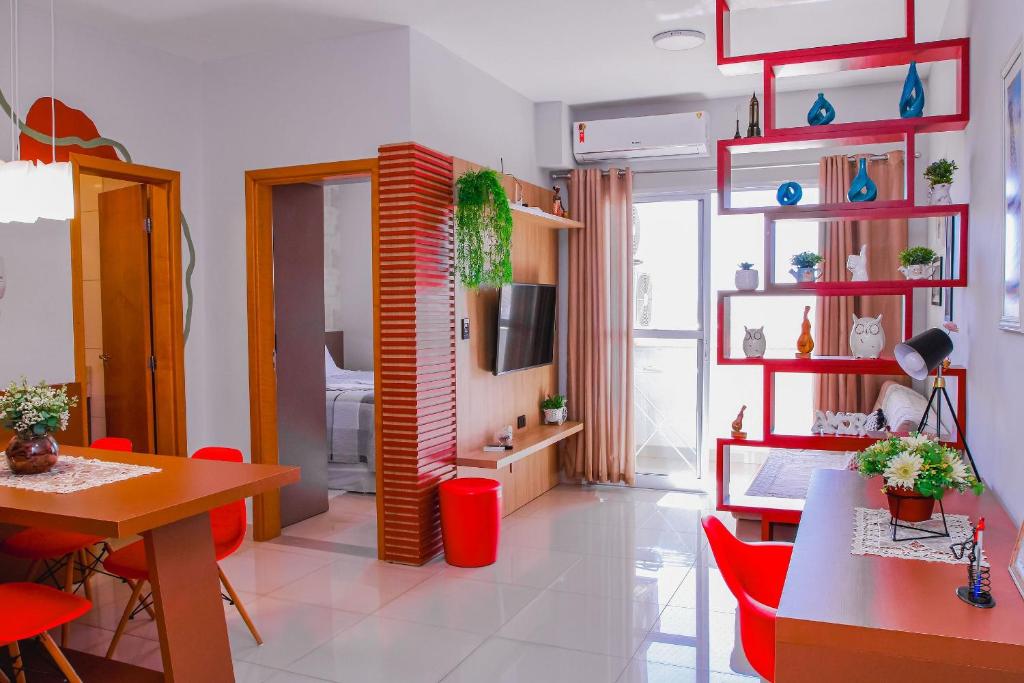 a living room with red chairs and a dining room at Acomodação Extraordinária em sua viagem - LoftFelau in Cuiabá