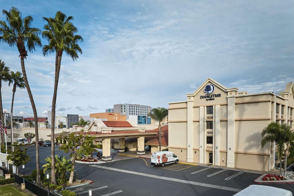 a building with a car parked in a parking lot at Doubletree by Hilton Buena Park in Buena Park