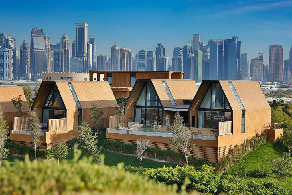 zwei modulare Häuser mit einer Stadt im Hintergrund in der Unterkunft Katara Hills Doha, Lxr Hotels & Resorts in Doha
