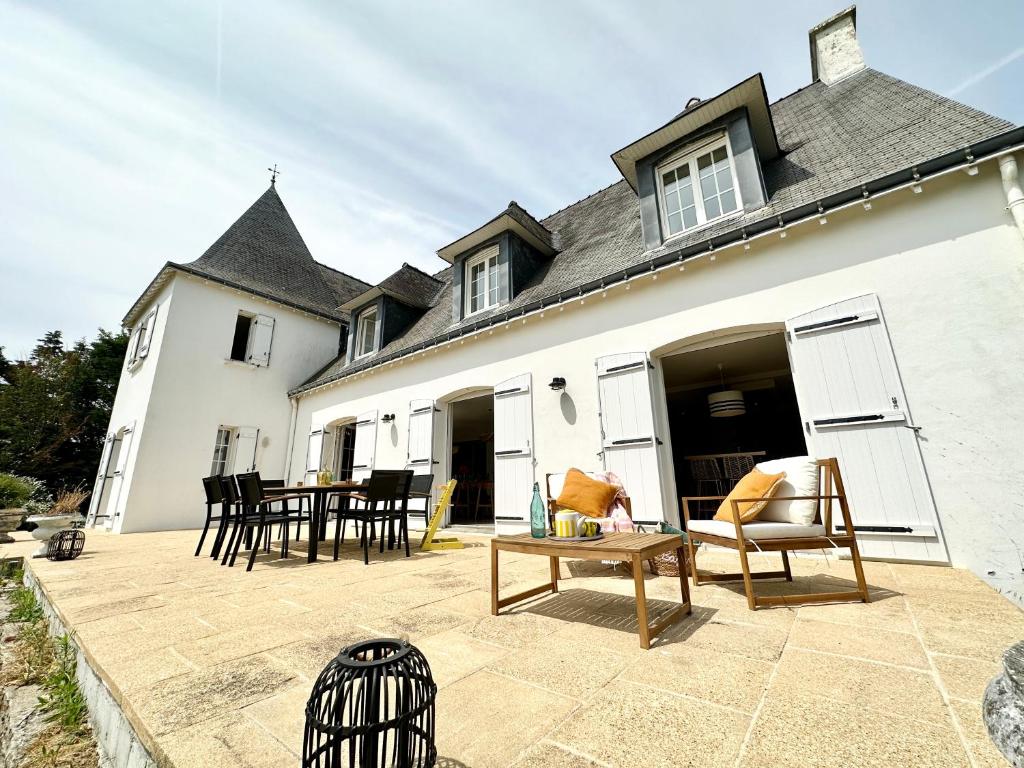 a patio with chairs and a table in front of a house at LUXURY ! Maison spacieuse de standing – Proche des plages in Ploemeur