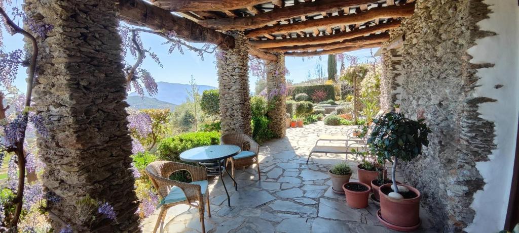 un patio con mesa, sillas y pared de piedra. en Cortijo Opazo, en Pórtugos