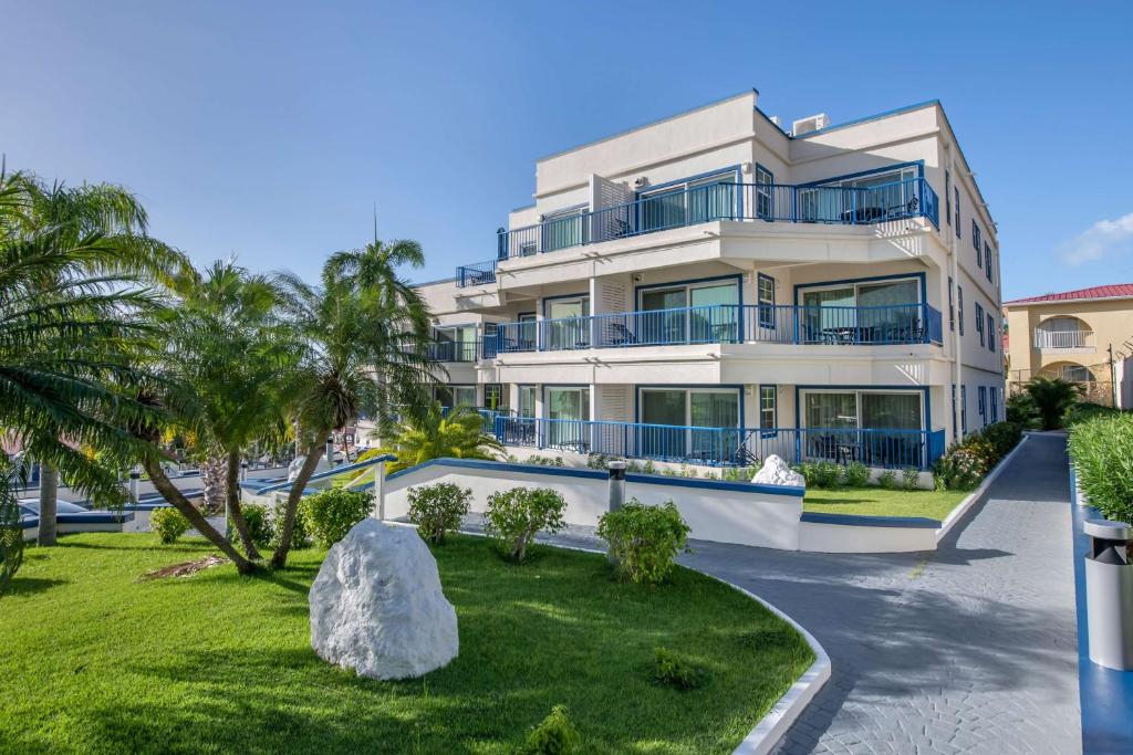 a large white building with palm trees in front of it at Hilton Vacation Club Flamingo Beach Sint Maarten in Simpson Bay