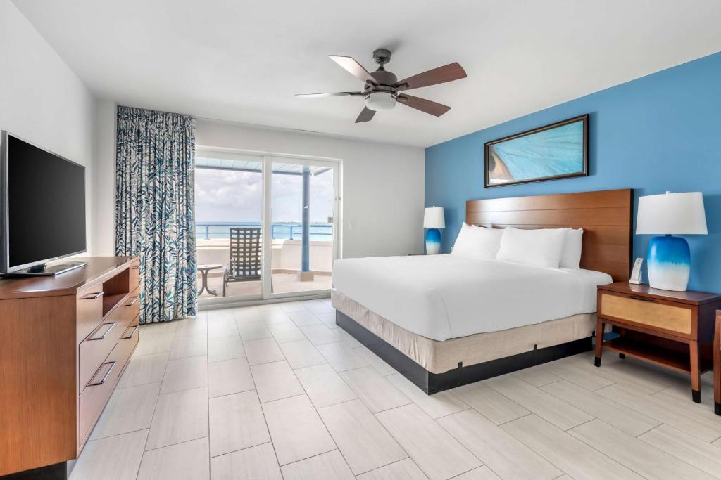 a bedroom with a bed and a television and a balcony at Hilton Vacation Club Flamingo Beach Sint Maarten in Simpson Bay