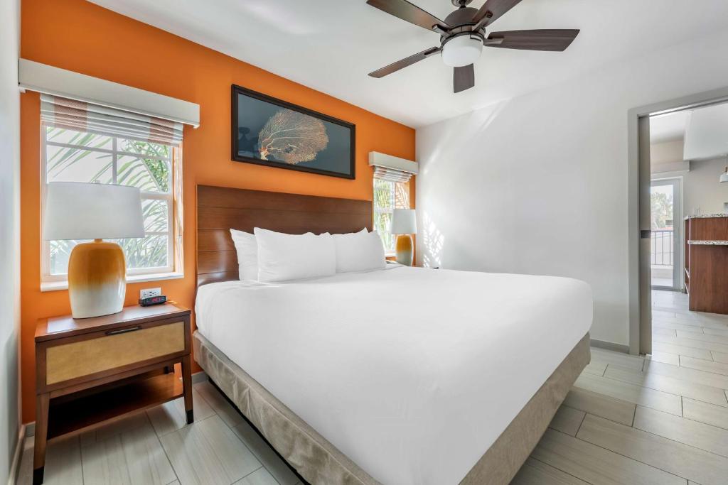 a bedroom with a white bed and an orange wall at Hilton Vacation Club Flamingo Beach Sint Maarten in Simpson Bay