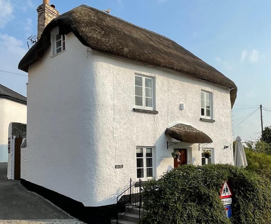 a large white house with a thatched roof at Tubs Cottage in Kingsteignton