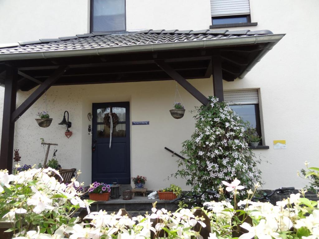 une maison avec une porte bleue et des fleurs dans l'établissement Ferienwohnung Vogt, à Mertloch