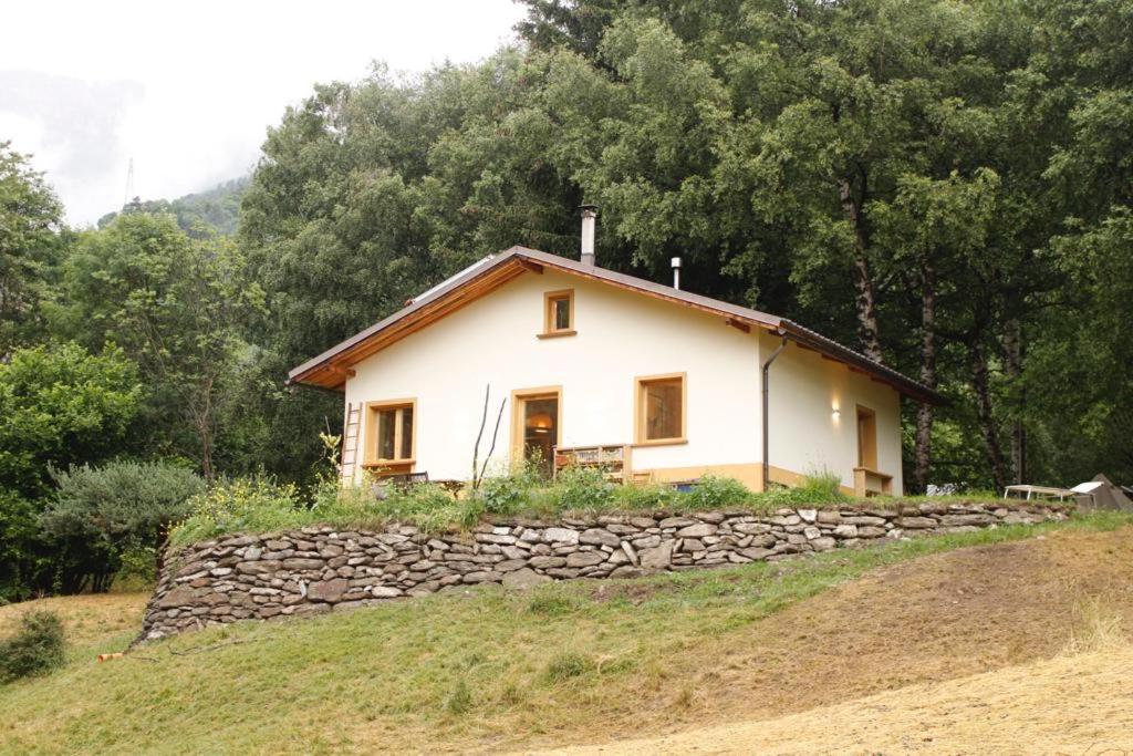 ein Haus auf einem Hügel mit einer Steinmauer in der Unterkunft LA CASA NEL BOSCO 