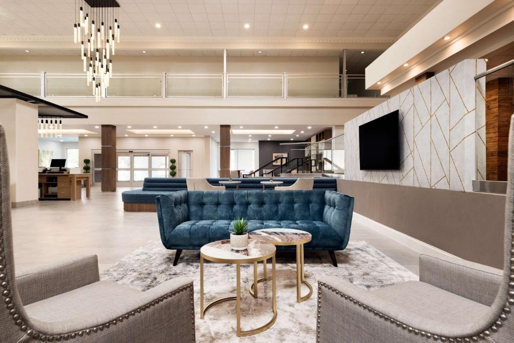 a lobby with blue couches and a tv and a table at Doubletree By Hilton Fort Worth South in Fort Worth