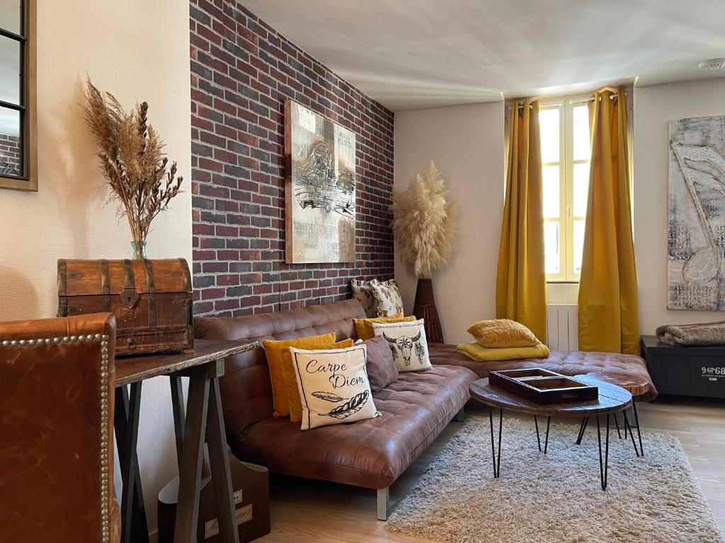 uma sala de estar com um sofá de couro e uma parede de tijolos em Carpe diem em Honfleur