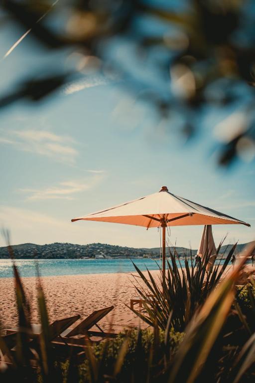ein Sonnenschirm am Strand in der Nähe des Wassers in der Unterkunft Les Prairies de la Mer in Grimaud