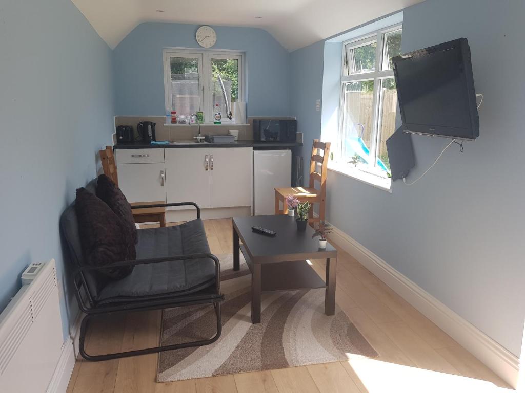 een woonkamer met een stoel, een tafel en een televisie bij Cosy Studio Luton in Luton