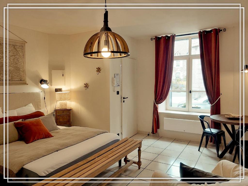 a bedroom with a bed and a table and a window at APPART HOTEL Place des Jolis Rêves in Riom-ès-Montagnes