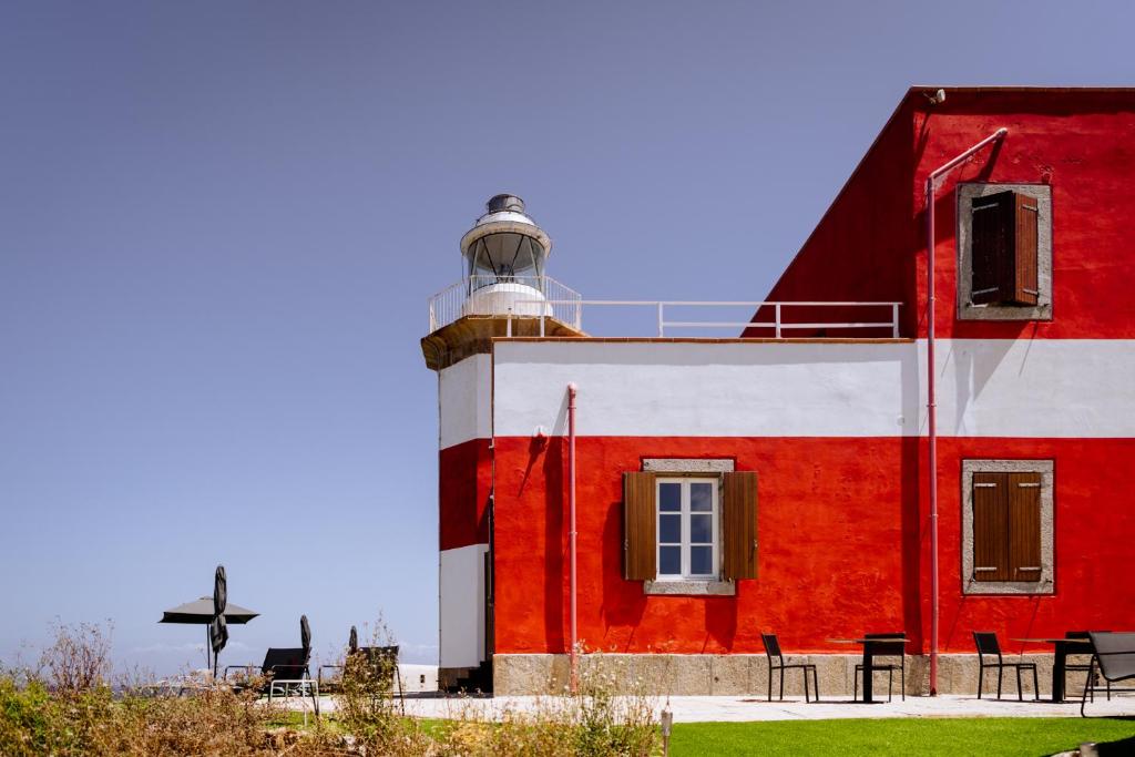 - un bâtiment rouge et blanc avec un phare dans l'établissement Resort Faro di Punta Fenaio, à Campese