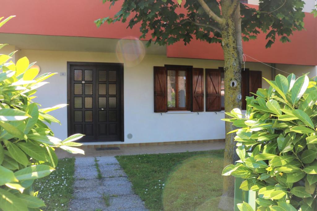 una casa con una puerta negra y ventanas en Villa Katia, en Bibione